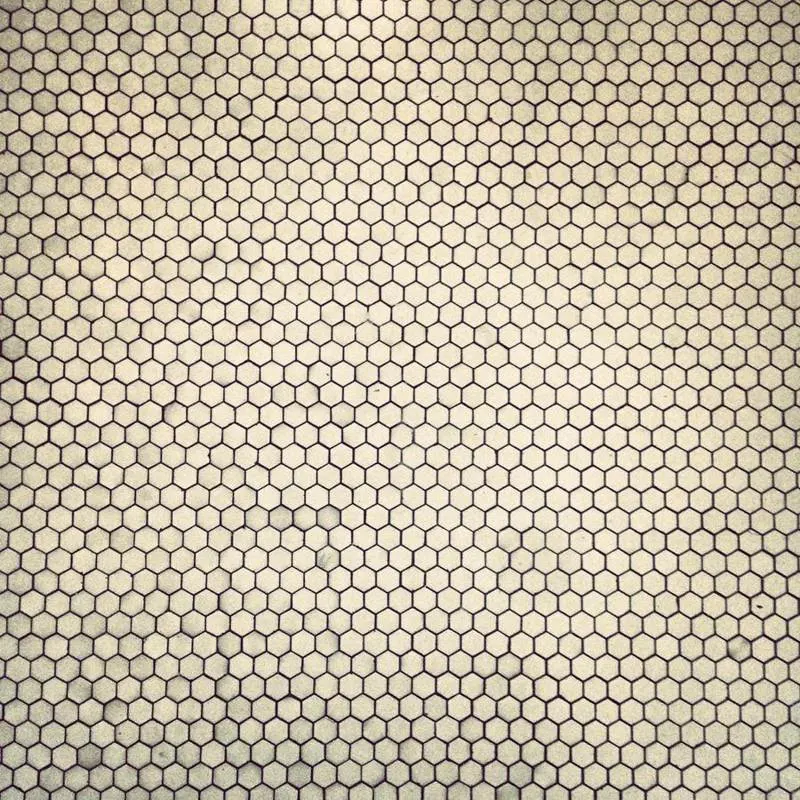 Small pale hexagonal mosaic tiles in a repeating pattern