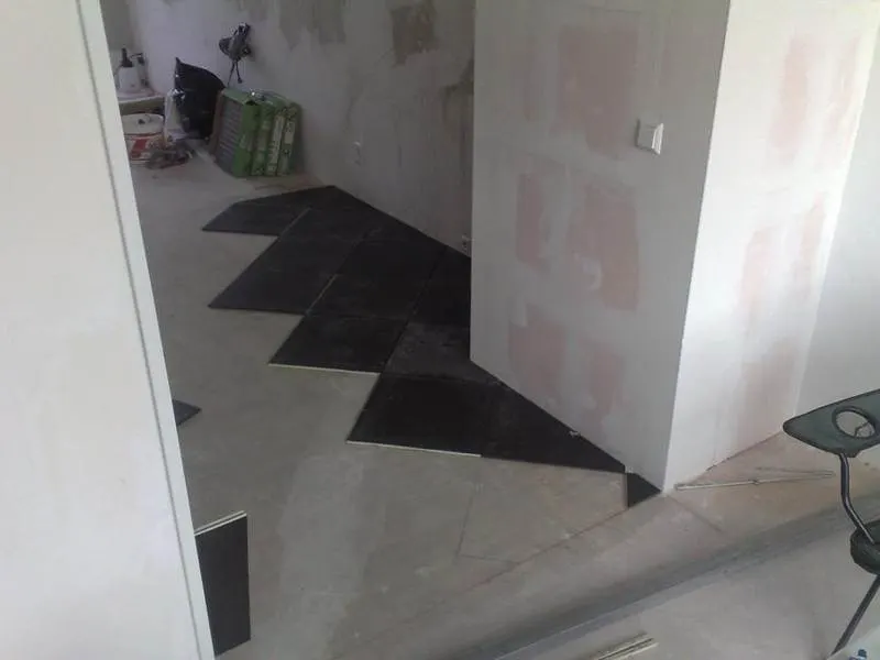 Contrasting pale and dark floor tiles around an interior corner