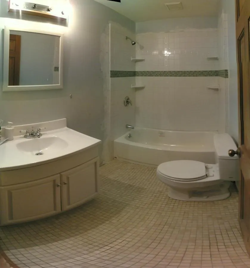 Bathroom with pale tiled walls and a small mosaic floor