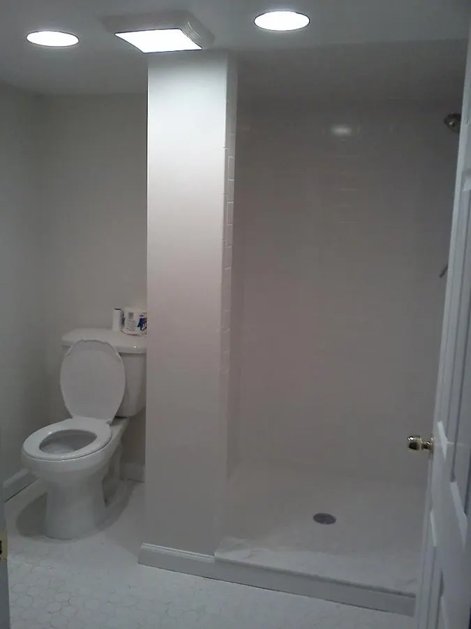 Minimal bathroom with pale floor tiles and a glass shower screen