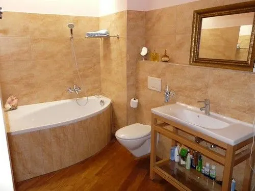 Bathroom with warm stone-effect wall tiles, a bathtub and a timber vanity