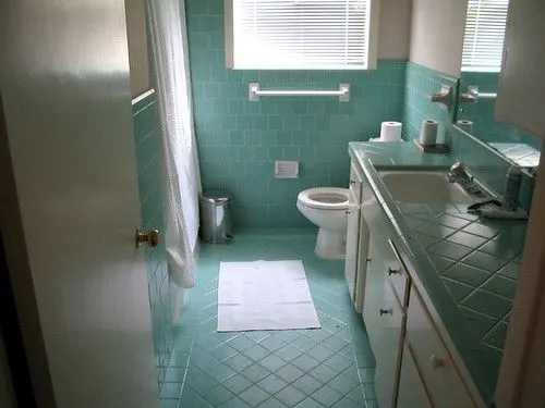 Bathroom with teal wall and floor tiles around a shower enclosure