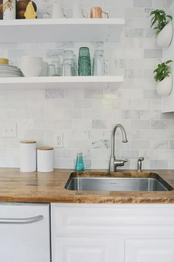 White kitchen with a herringbone tiled backsplash and open shelves