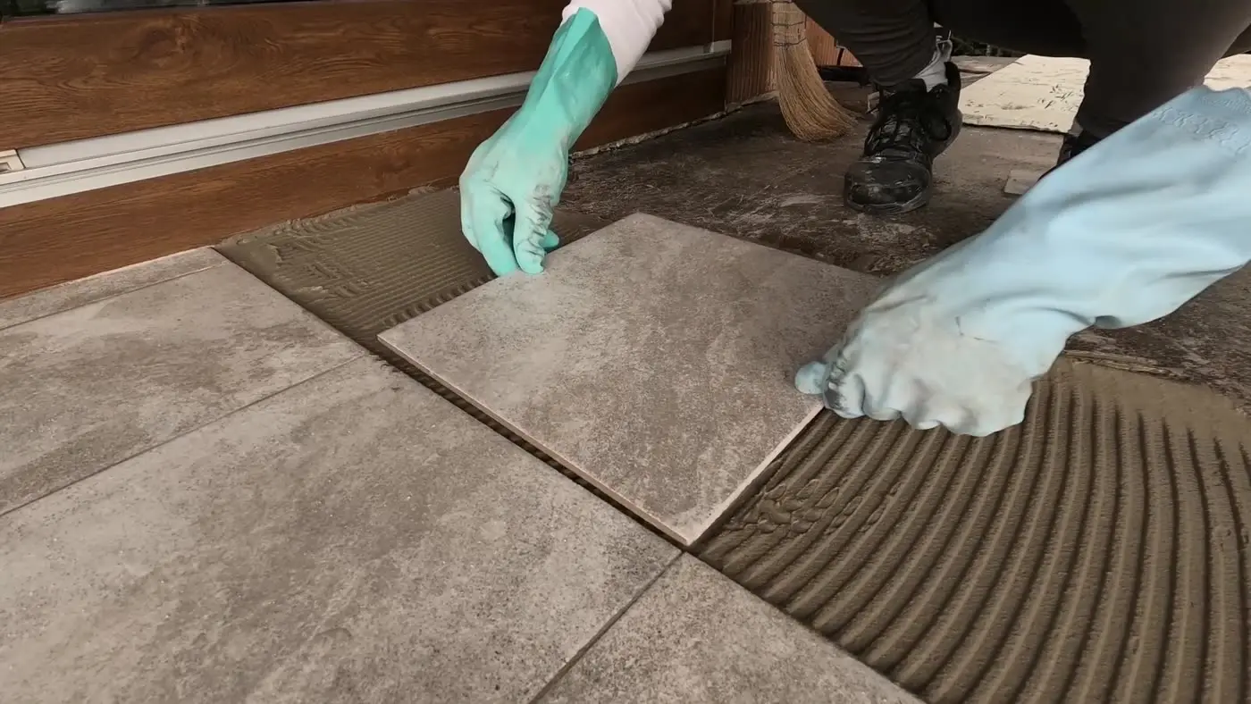 Tiler setting a floor tile into fresh adhesive and checking it for level