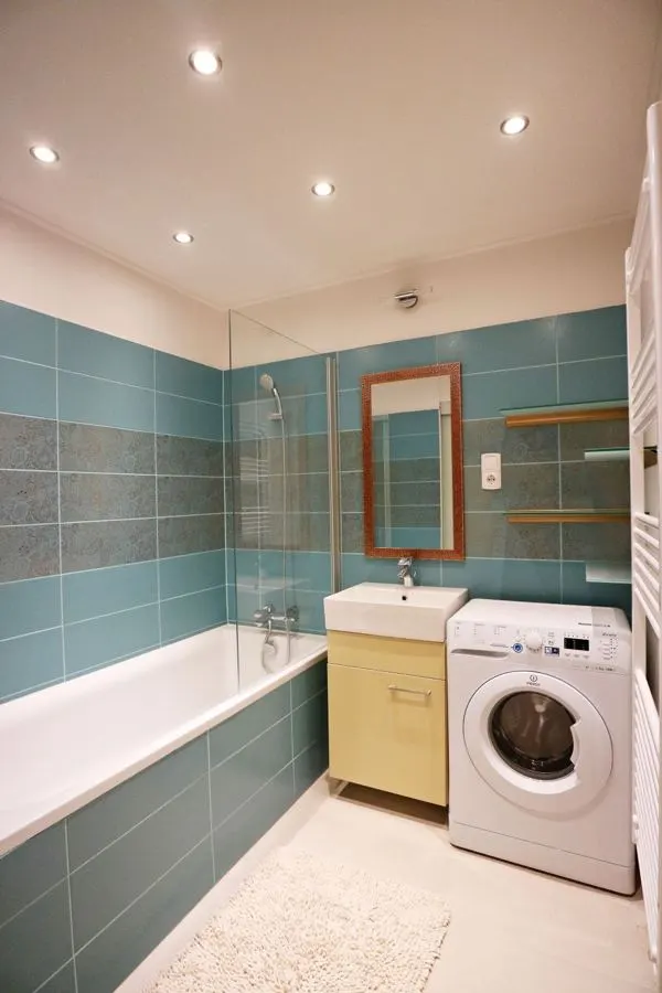 Bathroom with blue-green wall tiles and a white bathtub