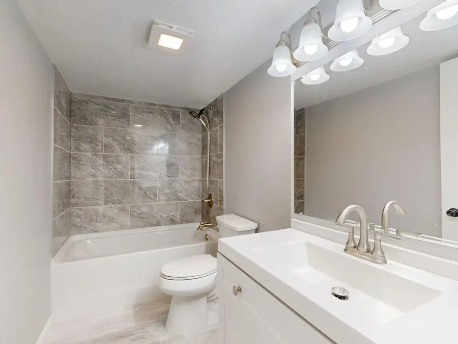 Bathroom with white cabinets and grey stone-pattern shower tiles