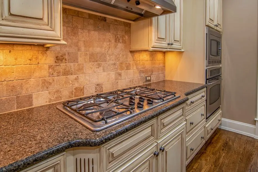 Warm beige stone backsplash above a gas hob