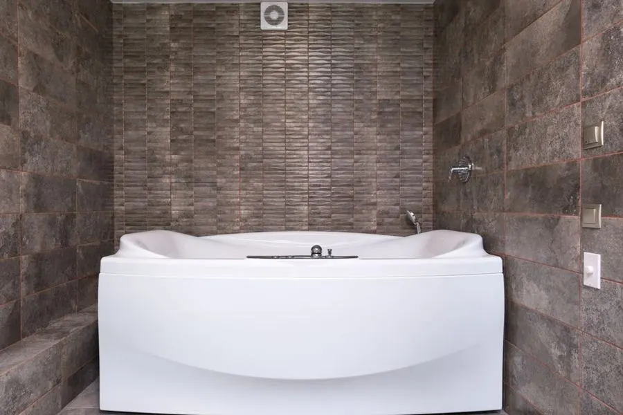 Bathroom with a freestanding tub against textured brown tiles