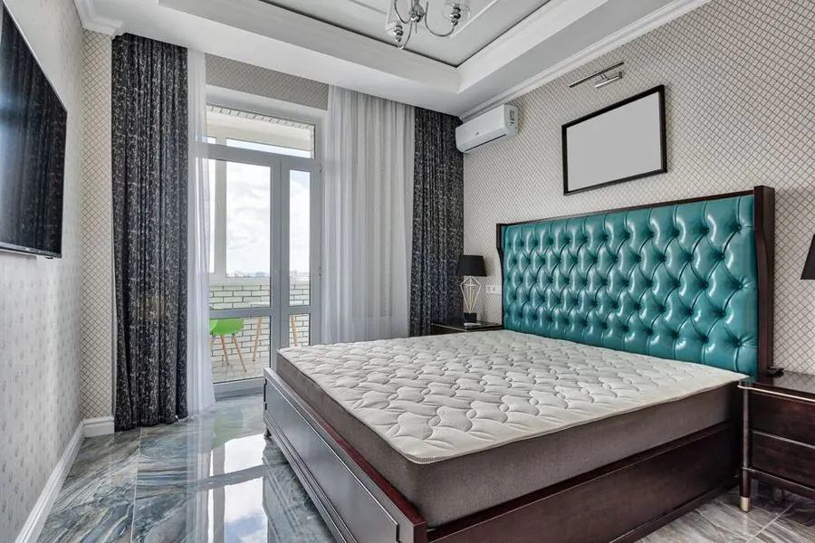 Bedroom with grey stone-pattern flooring and a teal upholstered bed