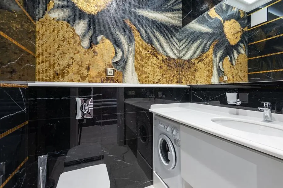 Bathroom with dark stone walls and a decorative gold feature panel